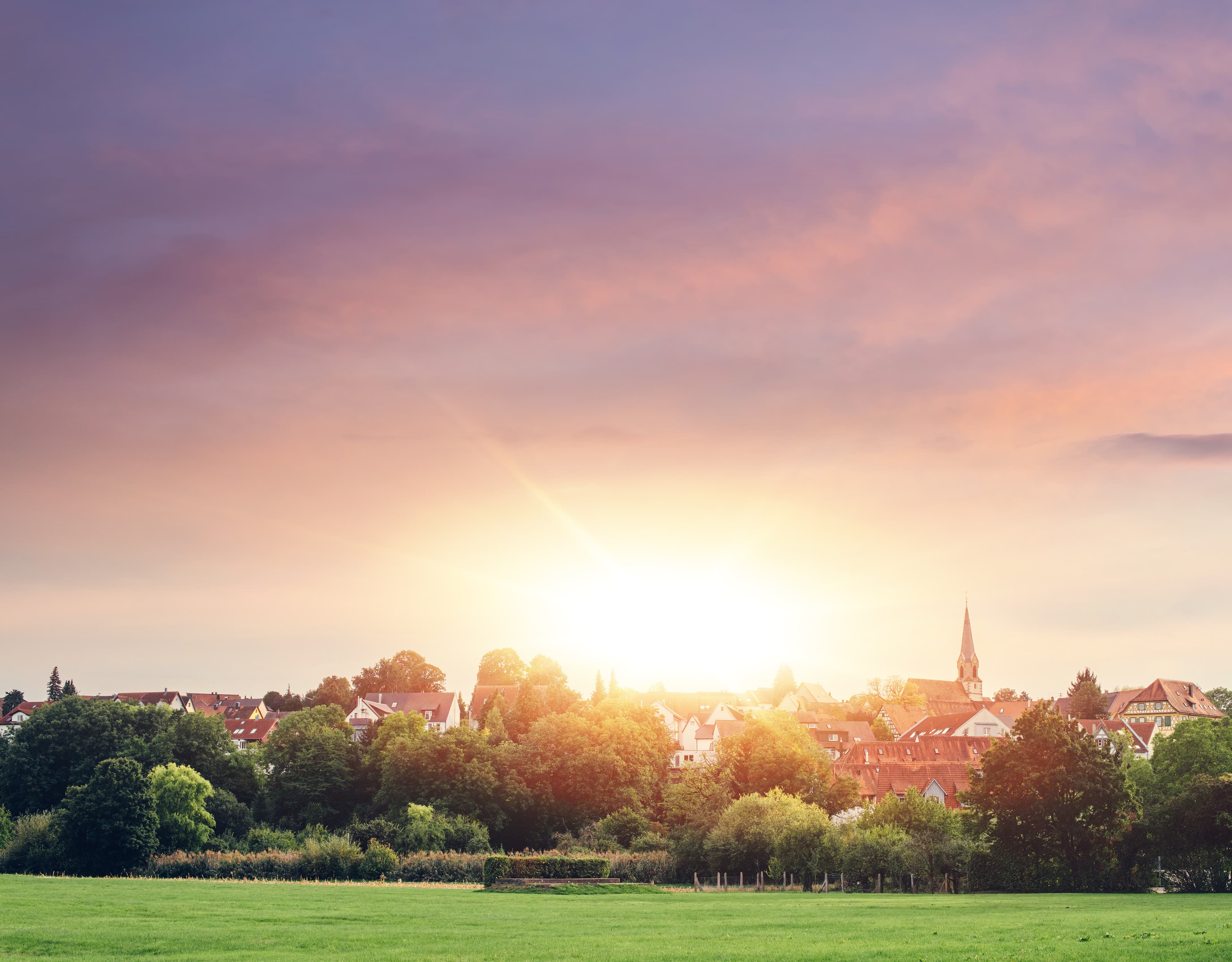 Blick über Pleidelsheim bei Sonnenuntergang mit Kirchturm und umliegenden Feldern.